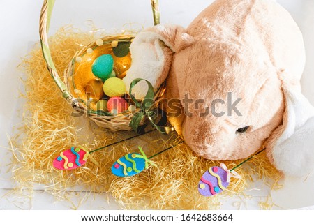 A plush rabbit and a basket with colorful Easter eggs. Easter decoration.