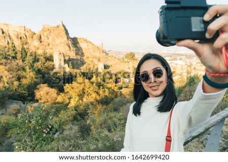 Happy Asian woman tourist is taking selfie shot with Narikala Fortress in Tbilisi, Georgia.