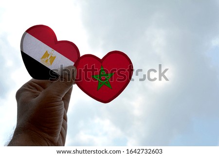 Hand holds a heart Shape Egypt and Morocco flag, love between two countries