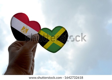 Hand holds a heart Shape Egypt and Jamaica flag, love between two countries