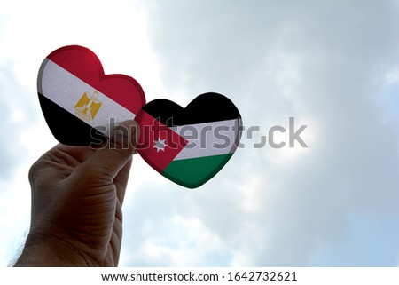 Hand holds a heart Shape Egypt and Jordan flag, love between two countries