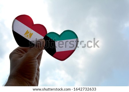 Hand holds a heart Shape Egypt and Kuwait flag, love between two countries