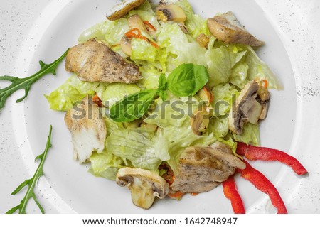 Leaves of an iceberg with tomatoes, chicken, bacon, croutons and Caesar sauce in a white round plate. On a white plate. Close-up