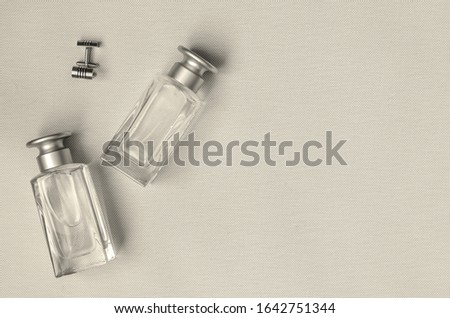 Glass bottles for perfumes and cuff links on a light background. Set of fine cuff links and Two bottles. View from above. Selective focus. Monochrome photo