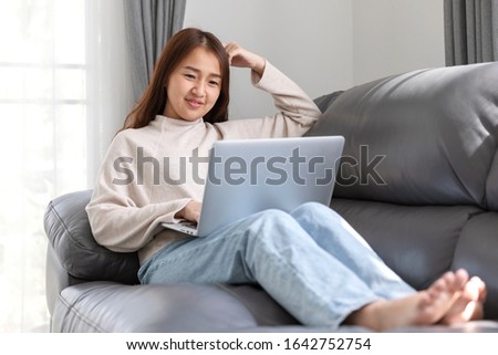 Young woman doing research work for her business, Smiling woman sitting on sofa relaxing while browsing online shopping website, technology woman concept for alternative office freelance stock photo.