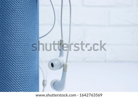 Wireless portable speaker and white headphones for connecting to other device on a white background. 