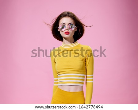 Pink background fashionable woman glasses makeup and yellow clothes