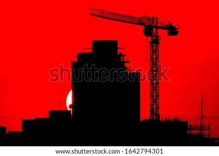 Building under construction with crane and red sunset