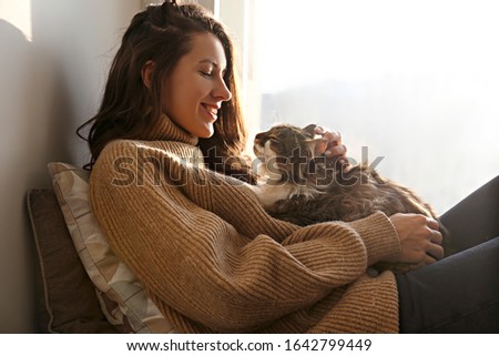 Portrait of young woman holding cute siberian cat with green eyes. Female hugging her cute long hair kitty. Background, copy space, close up. Adorable domestic pet concept. Royalty-Free Stock Photo #1642799449