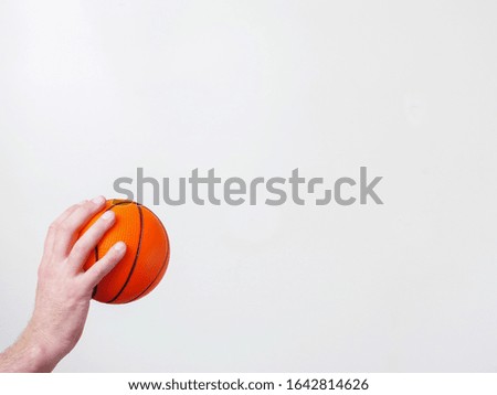 Mini basketball in a hand on a bright background. Copy space.