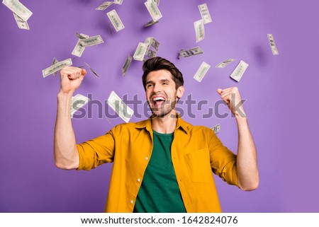 Photo of cheerful crazy positive excited man browin haired wearing yellow shirt screaming yeah standing in rain of money isolated violet pastel color background