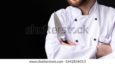 Unrecognizable Chef Man Holding Knife Posing Standing On Black Studio Background. Cropped, Panorama, Free Space