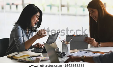 Photo of business development team discussing/brainstorming/talking/meeting about them new project while sitting/standing at the modern meeting table with comfortable office as background.