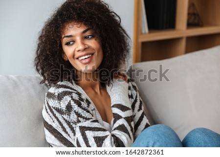 Image of a positive pleased optimistic beautiful young african woman indoors at home.