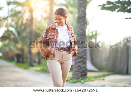 Young beautiful woman wearing jacket smiling happy and confident. Standing with smile on face at the town park
