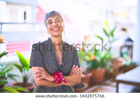 Middle age beautiful grey-haired woman wearing dress and bandana on wrist smiling happy and confident standing with a smile on face at terrace