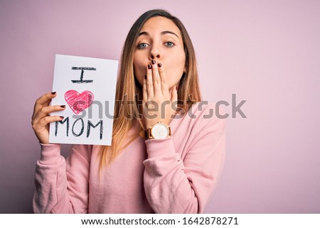 Young beautiful woman holding paper with love mom message celebrating mothers day cover mouth with hand shocked with shame for mistake, expression of fear, scared in silence, secret concept