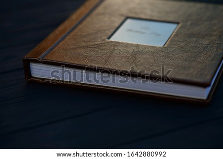Texture of natural brown leather on the cover of a wedding photo book on a dark wooden background. Soft selective focus.