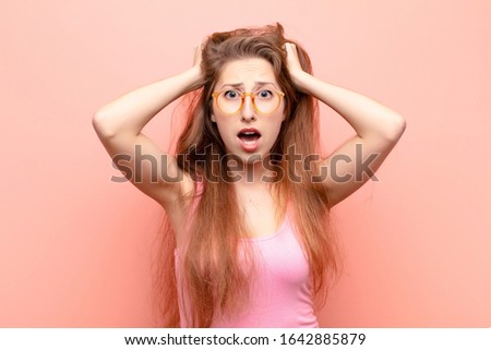 yound blonde woman feeling stressed, worried, anxious or scared, with hands on head, panicking at mistake