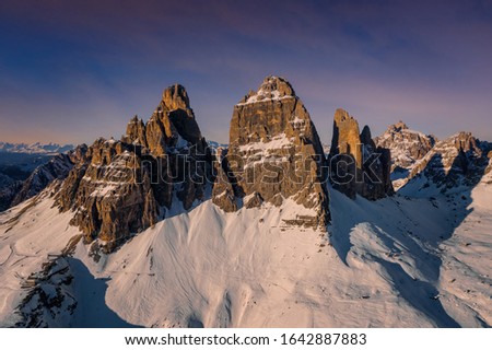 Colorful sunset sunset in Dolomites mountains, three peaks of Tre Cime di Lavaredo in snowy and cloudy background. Italy, Europe. January 2020