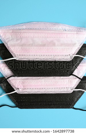 medical masks black and pink colors to cover the mouth and nose for protection from bacteria on a blue background. vertical photo