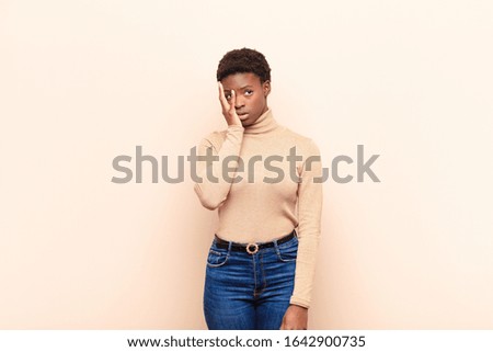 young pretty black womanfeeling bored, frustrated and sleepy after a tiresome, dull and tedious task, holding face with hand