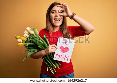 Beautiful woman holding paper with love mom message and tulips celebrating mothers day with happy face smiling doing ok sign with hand on eye looking through fingers