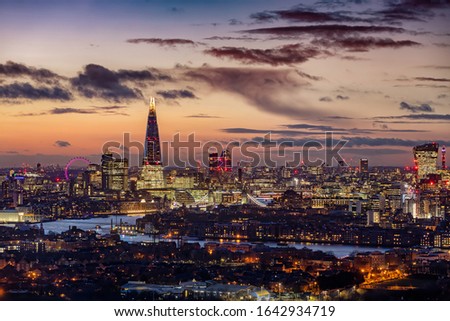 Elevated view to the modern London skyline with illuminated skyscrapers and various tourist attractions during dusk time, United Kingdom