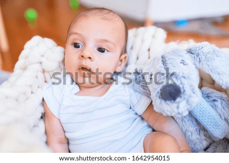 Adorable baby lying down over blanket on the floor at home. Newborn relaxing and resting comfortable with teddy bear