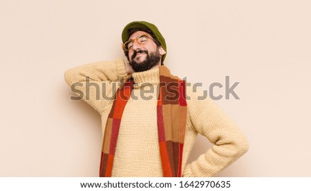 young cool bearded man smiling and feeling relaxed, satisfied and carefree, laughing positively and chilling