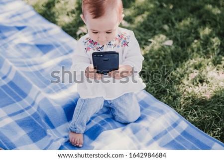 happy baby using mobile phone outdoors. technology concept