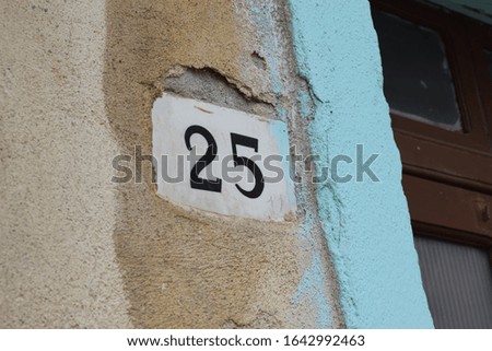 Number tag on the wall of an house with "25" written on it