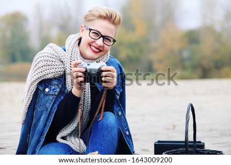 Free and happy young girl or woman taking photo on a retro camera outdoors at spring. Holiday, vacation, hobby concept.