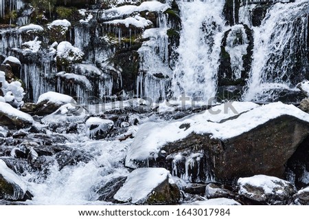 Shypit waterfall near Pylypets, Ukraine, winter waterfall picture, half frozen water flow, ice and snowy stones