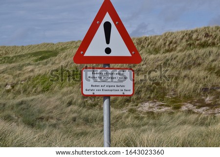 danger sign in danish and geran in the dunes saying be aware of wire in water