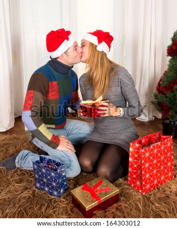 Romantic Young Happy Couple Christmas hats kissing on rug 