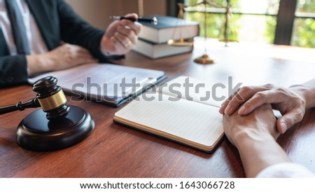Lawyer working with client discussing contract papers with brass scale about legal legislation in courtroom, consulting to help their customer.