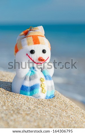 Smiley toy snowman at sea beach. Holiday concept for New Years and Christmas Cards.