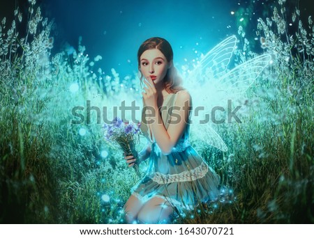 Art photo fantasy pixie butterfly. young fairy with glow wings holds bouquet flower. dark blue backdrop fabolous night Firefly star glitter light. Fingers show sign silence. cute face, makeup red lips Royalty-Free Stock Photo #1643070721