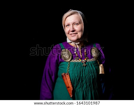 Mature woman in a Viking costume, 10th century, region - Denmark. Green Hangerok dress and turtle broshes. Close up  Portrait of a woman who is fond of living history. 
