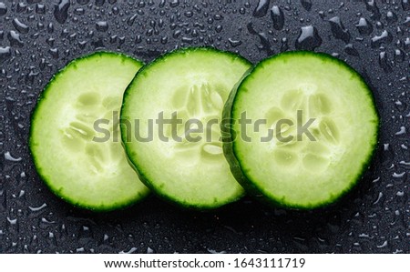 Isolated cucumber slices. Pieces of fresh cucumber isolated on black background. Closeup of cucumber details covered with water droplets