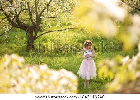 Young attractive girl walks in spring green park enjoying flowering nature. Healthy smiling girl spinning on the spring lawn. Allergy without.