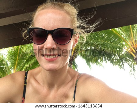 Happy friendly blonde woman traveling Asia relaxing at a cottage with palms at the Phillipin beach