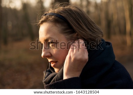 Woman adjusts headphones in ears