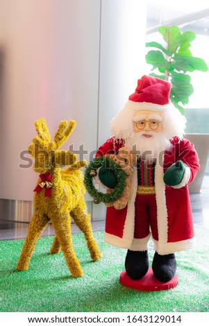 Santa Claus doll holding a teddy bear With a reindeer doll Used to decorate the Christmas festival