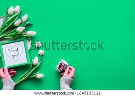 Frame with text "Thank you". Hands with coffee cup and white Bunch of white Spring tulips, frame with text and heart shape, hand with espresso coffee cup. Vibrant neo mint green flat lay, top view.