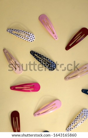 Colorful trendy hair clips on bright yellow background. Top view.
