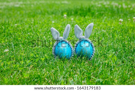 Blue Easter eggs with silver bunny ears on a grass. Easter holiday decoration.