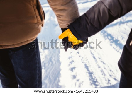 hands of a couple in love in mittens close-up on a snow background