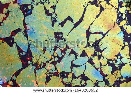 Abstract oily surface of a cup of tea, looking like drifting continents or ice floes; color photo.